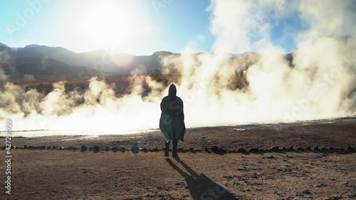 BACK WOMAN WHEN SUN IS RISING IN THE ATACAMA DESERT WITH PONCHO