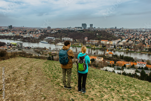Two young backpackers enjoying view of Prague city skyline and Vltava river,Czech Republic.Attractive landscape with deep valley,hiking trails,Prague panorama in background.Active citylife style.