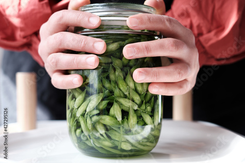Nails in lockdown. Lacto fermented wild garlic stems in a jar. Keeping the jar in both hands. Foodie background pattern.  photo