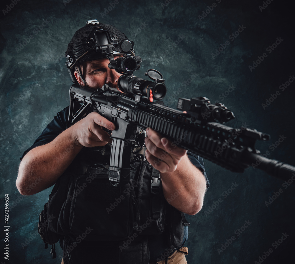 Dangerous and armed soldier aims a machine rifle in dark background Dangerous and armed soldier aims a machine rifle in dark background