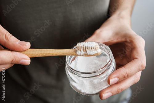 Tableau sur toile Woman holds bamboo toothbrush and soda powder in her hands