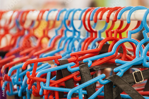 Many plastic colorful hangers on clothes rail. Store concept, sale, design, empty hanger