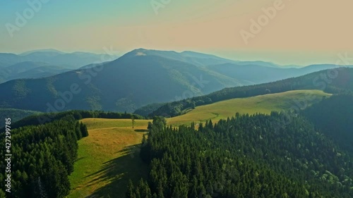 Aerial drone footage view of Carpathian mountains with a beautiful green meadow and hills. Tarcului Mountains, Romania. photo