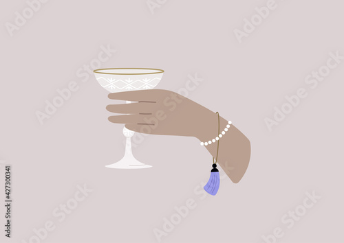 A celebration concept, an elegant hand holding a champagne saucer, classy lifestyle