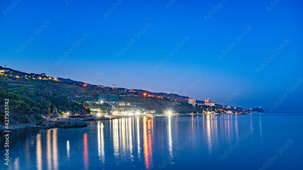 Green sea shore with residential buildings in the night Green sea shore with residential buildings in the night