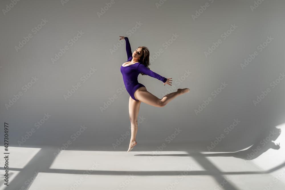 Sexy plus size model with big breasts in purple bodysuit jumping in studio Sexy plus size model with big breasts in purple bodysuit jumping in studio