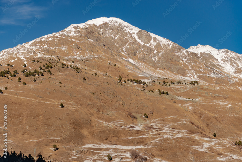 Elbrus region in the sunlight. High mountain with almost no snow. Rare trees on a steep mountain. Elbrus region in the sunlight. High mountain with almost no snow. Rare trees on a steep mountain.