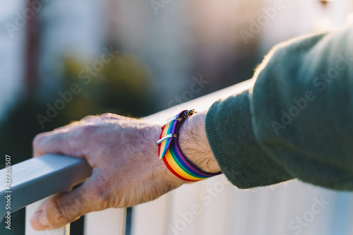 close-up view of a man s hand with an LGBT rainbow wristband.