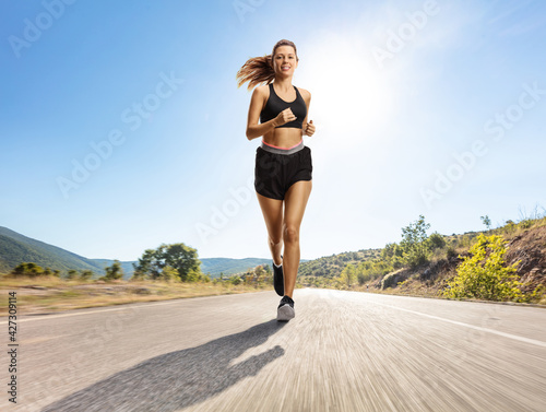 Full length portrait of a young woman jogging on a road