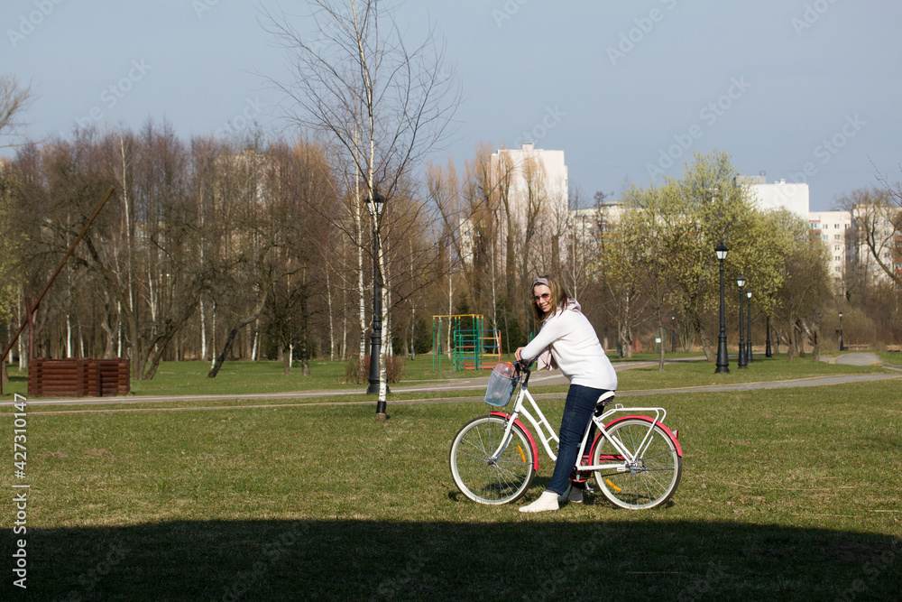 Girl on a bike ride in a spring park. Stands with a bike.