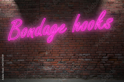 Neon Bondage hook lettering on Brick Wall at night