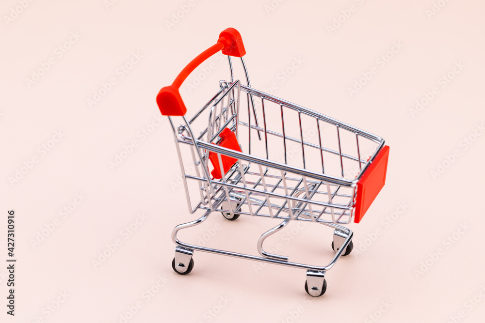 Shopping cart on beige background. Top view with copy space. Shop trolley at supermarket. Sale, discount, shopaholism concept. Consumer society trend Shopping cart on beige background. Top view with copy space. Shop trolley at supermarket. Sale, discount, shopaholism concept. Consumer society trend