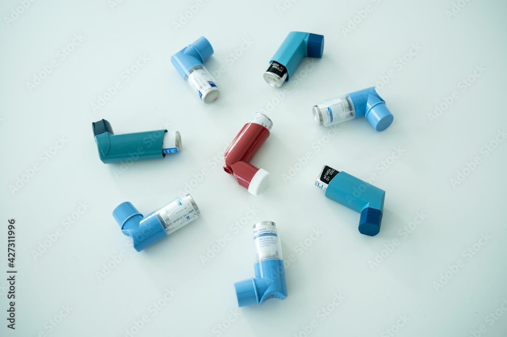 Various asthma spray inhalers on a white surface Various asthma spray inhalers on a white surface