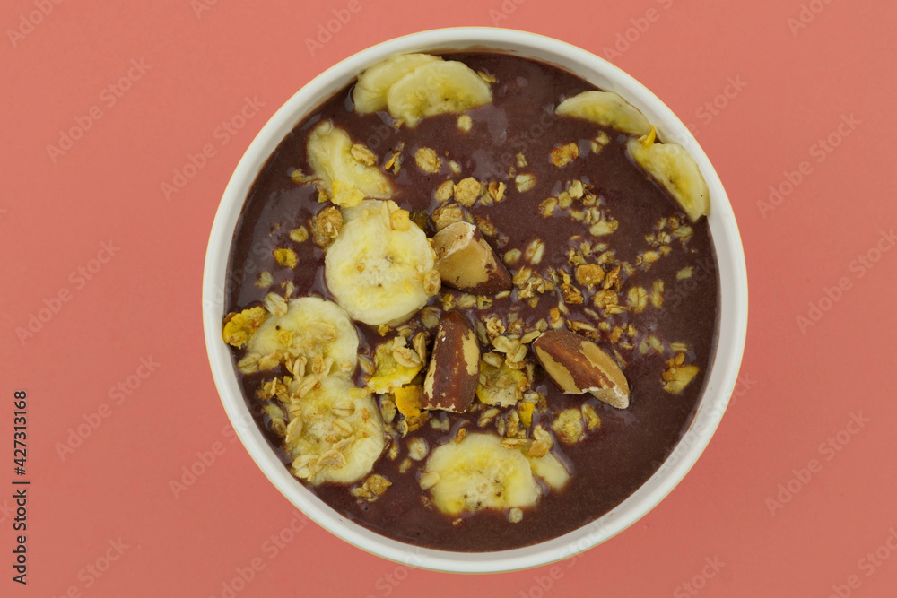 Brazilian açai in a white bowl with banana, granola and chestnuts. Top view. Brazilian açai in a white bowl with banana, granola and chestnuts. Top view.