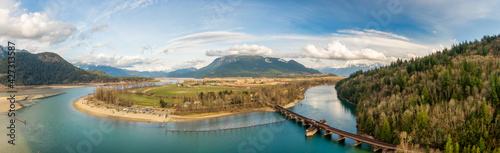 Aerial Panoramic View of a River in the valley surrounded by Canadian Mountain Landscape. Green Farms. Taken in Harrison Mills, Fraser Valley, East of Vancouver, BC, Canada.