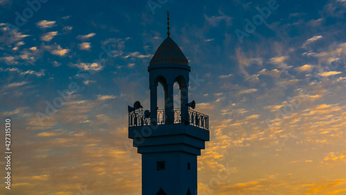 Photo minaret of mosque with blue yellow  cloudy sunset