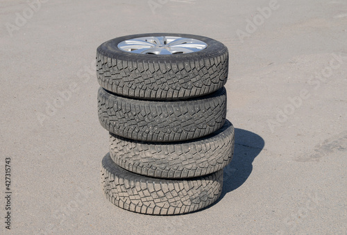 Four car wheels stand on top of each other on the pavement for seasonal tire changes photo