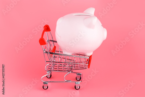 Bilde på lerret Piggy Bank with a shopping cart on a pink background
