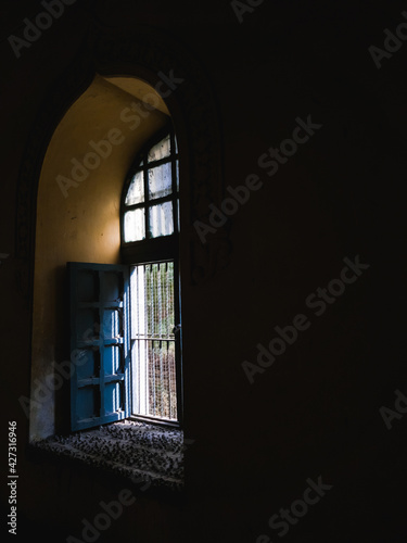A vintage window in a dark hall inside the ancient Thirumalai Nayak palace in the city of Madurai. photo