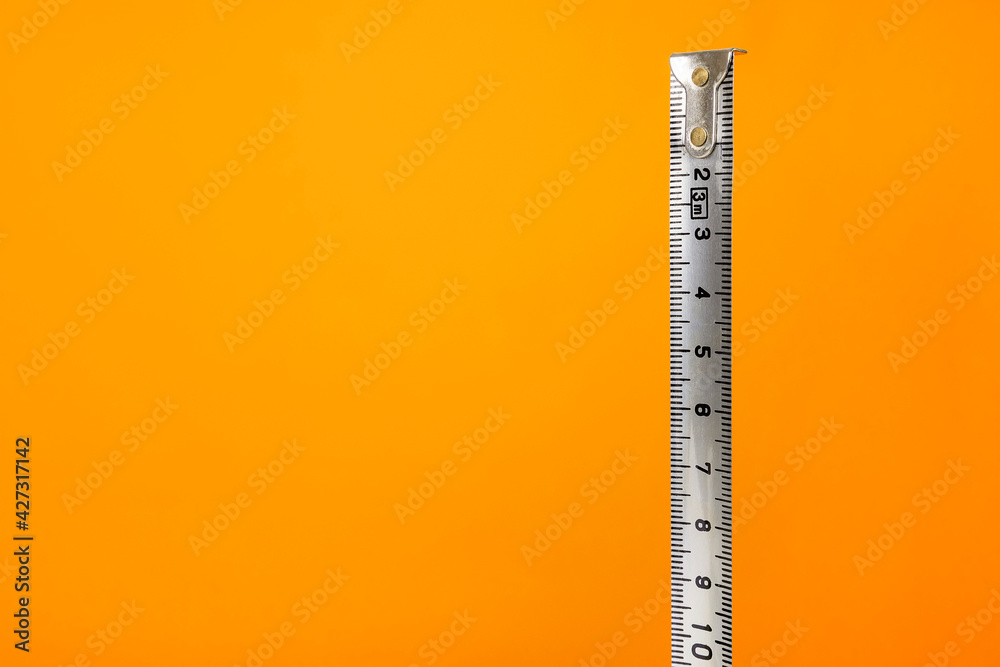 Measuring tape against bright orange background. Minimalistic, vivid colors. Measuring tape against bright orange background. Minimalistic, vivid colors.
