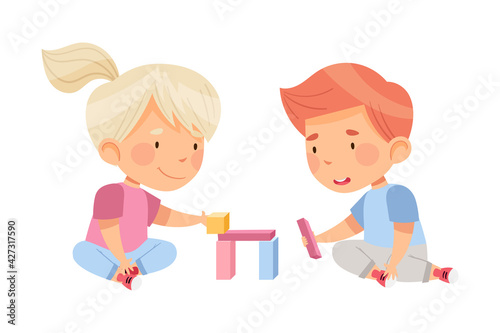 Excited Boy and Girl Sitting on the Floor in Nursery Playing Toy Blocks Vector Illustration