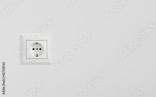 White electrical outlet on white plastered wall, close-up with copy space