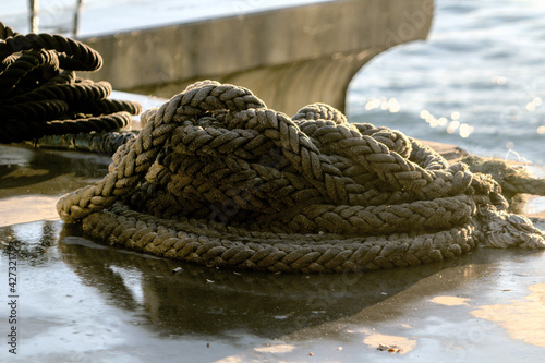 Wet strong rope piled up on a dock by seaside. 