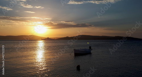Sunset over the sea. In the foreground is a fishing boat at anchor