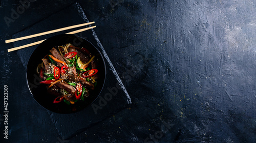 Stir fry soba noodles with beef and vegetables in wok on dark background, Asian noodles with beef WOK in black bowl