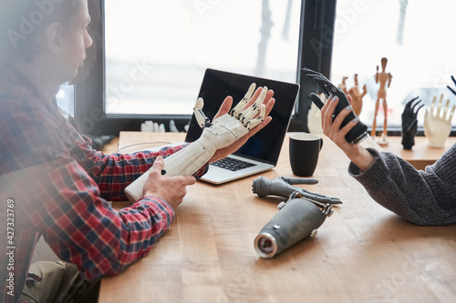 Male and female colleagues holding bionic prosthesis limbs and discussing it photo