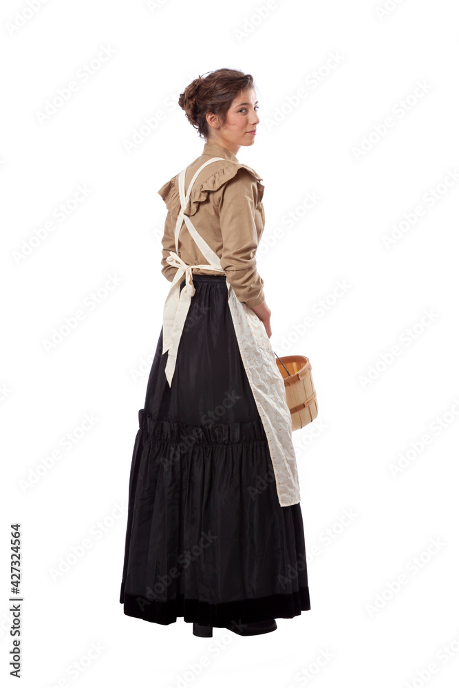 Young prairie woman with apron looking back and holding a basket isolated on white Young prairie woman with apron looking back and holding a basket isolated on white
