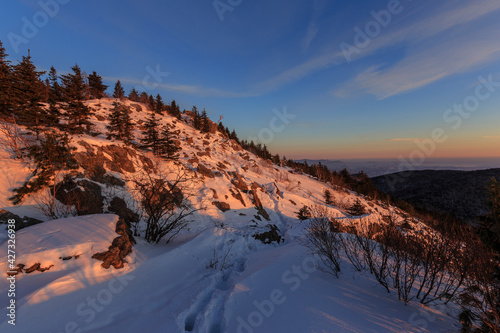 Travel to the Primorsky region. A path trodden in the snow at the top of a snow-capped mountain during a bright sunset.