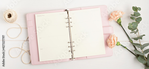 Open planner and flowers. Workspace with notebook. Freelance business, organization, wedding planning