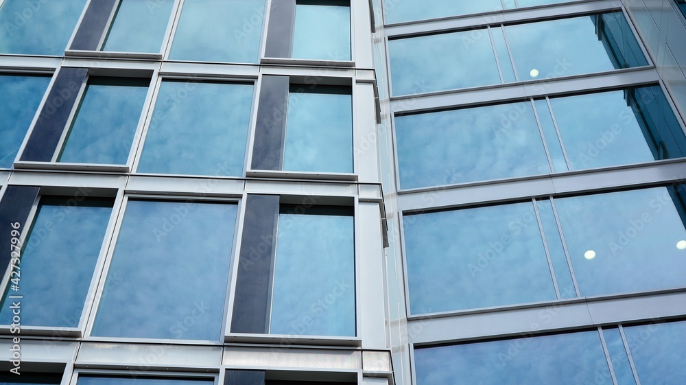 Glass clad facade of a modern building covered in reflective plate glass.