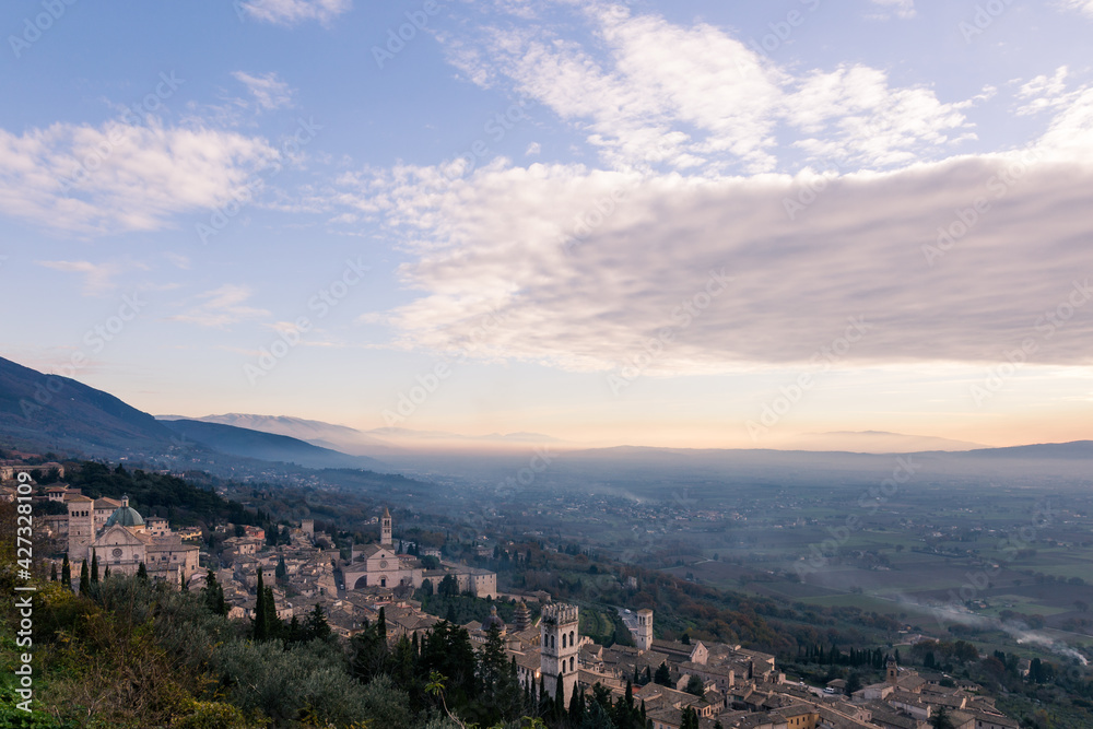An aerial view of Assisi town with low clouds at late afternoon