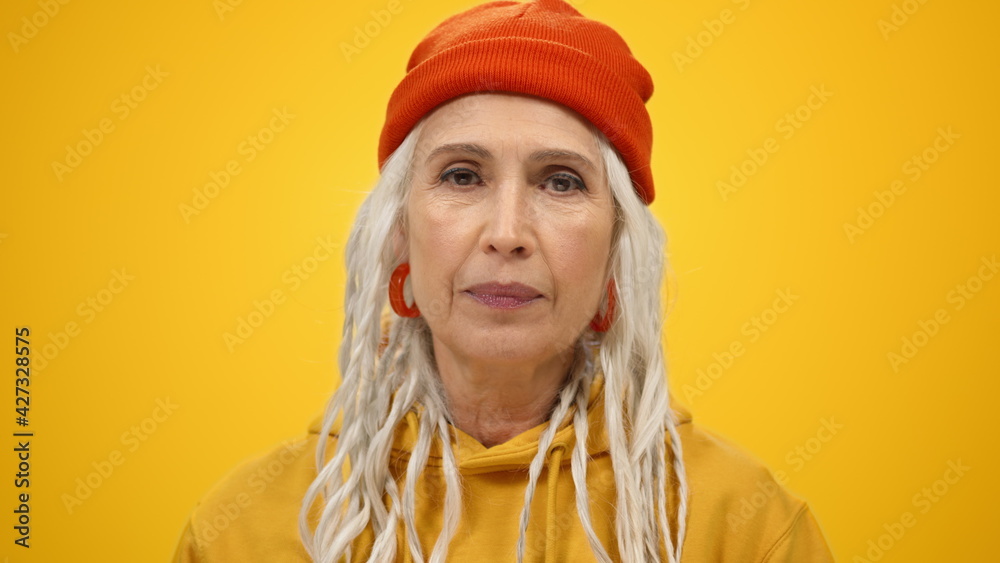 Joyful old woman posing camera inside. Smiling lady showing rock gesture indoors