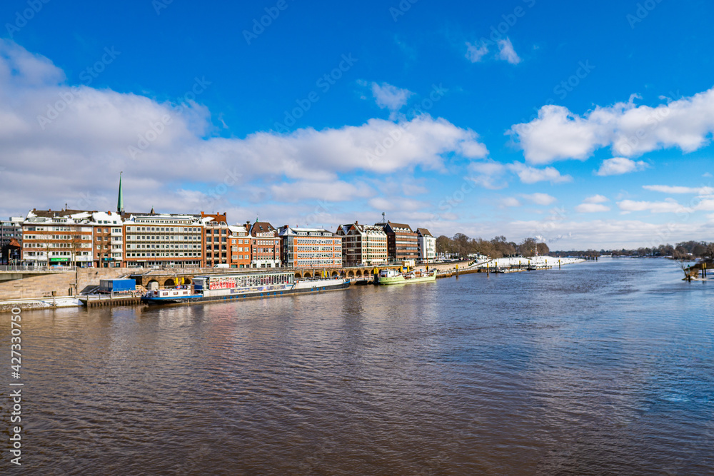 View from footbridge to river weser with some boats in the sunlight in bremen in winter
