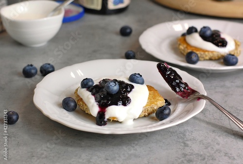 Whole grain pancakes with blueberries,yoghurt and jam on white plate