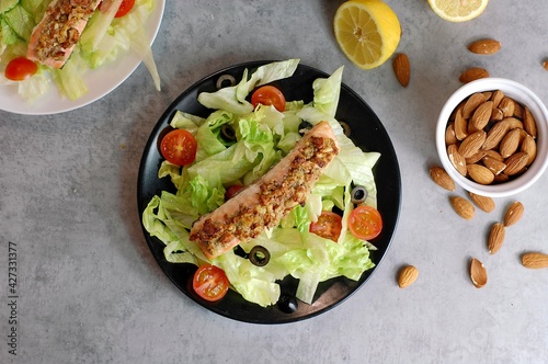 Fresh salad leaves with cherry tomato, olive with and roasted salmon with almont crust photo