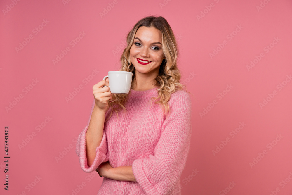 Drink coffee, enjoy a hot drink. A young woman in a warm pink sweater Drink coffee, enjoy a hot drink. A young woman in a warm pink sweater