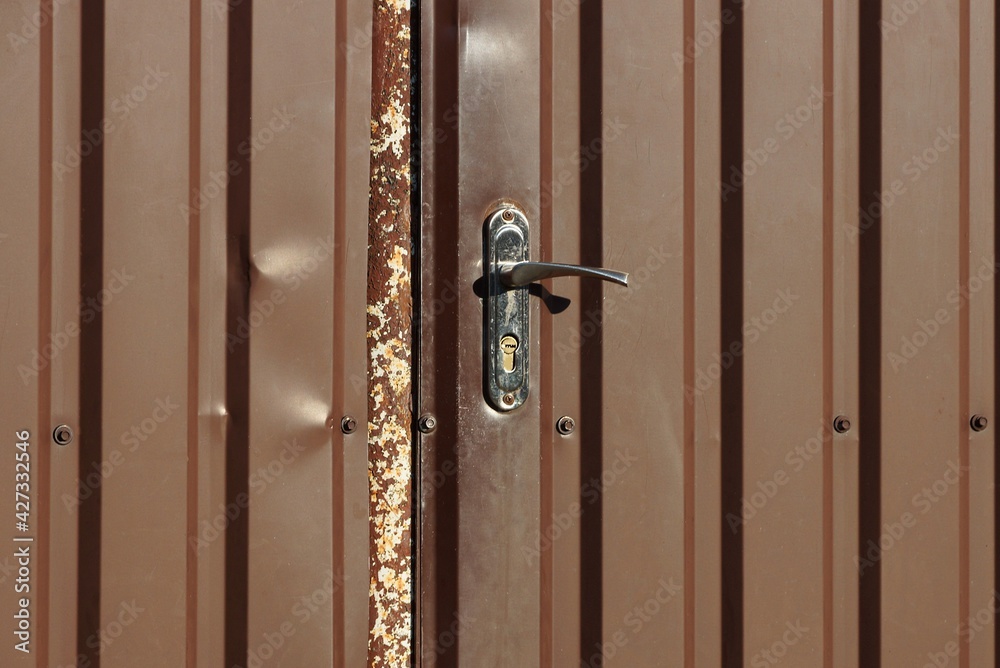 Obraz premium one old black metal doorknob on a brown closed iron door on the street