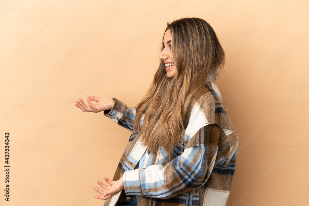 Young caucasian woman isolated on beige background with surprise expression while looking side Young caucasian woman isolated on beige background with surprise expression while looking side