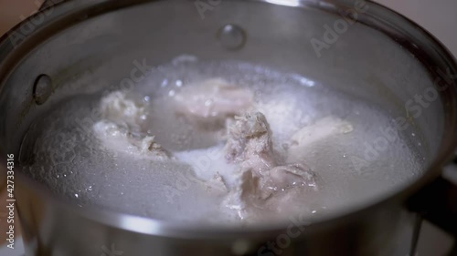 Boiling Chicken Fillets for Broth in a Saucepan on a Gas Stove. Boiling process, water evaporation, foam, bubbles. Cooking boiled, juicy, dietary meat. Food concept. Slow motion. Close-up. 180 fps. photo