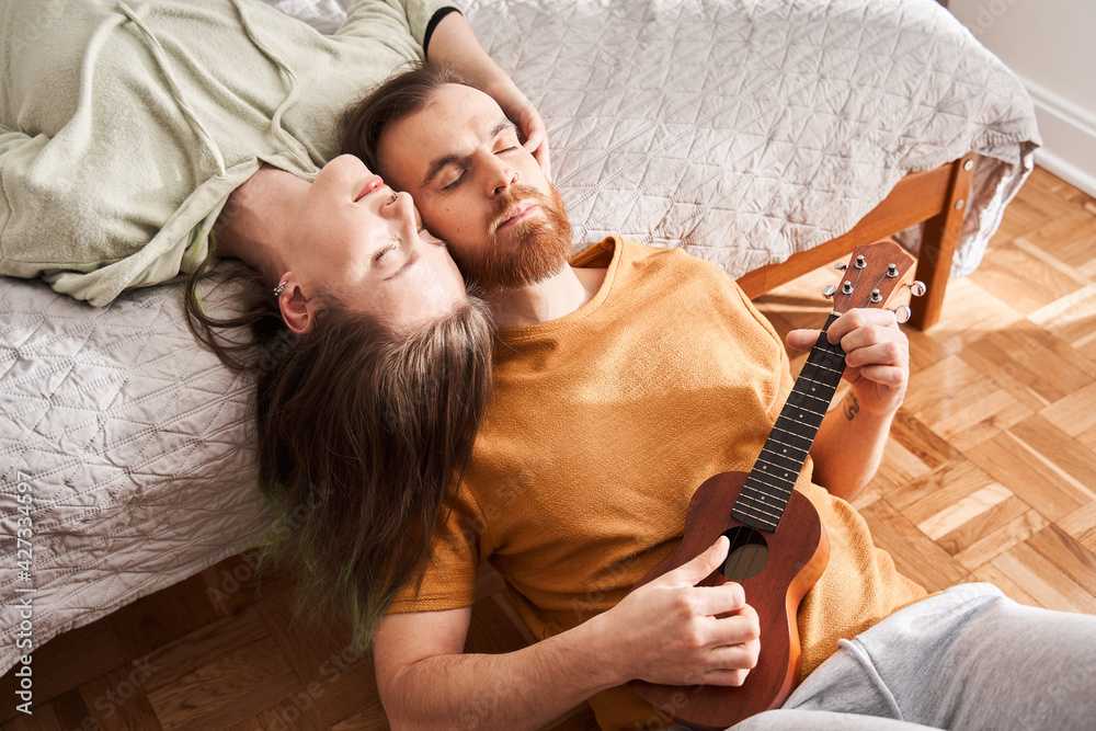 Loving couple enjoying of the music together while man is playing at the ukulele