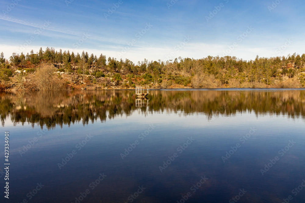 beautiful lake landscape, with a blue sky , and vibrant autumn colors reflecting your image in the water mirror, in Viseu, Portugal