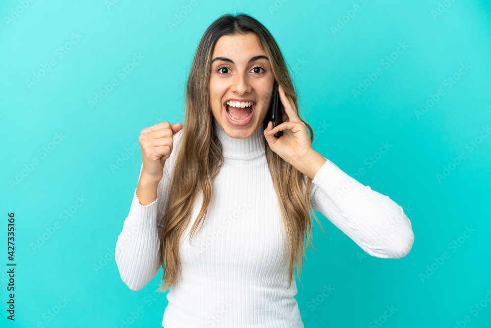 Fototapeta premium Young caucasian woman using mobile phone isolated on blue background celebrating a victory in winner position