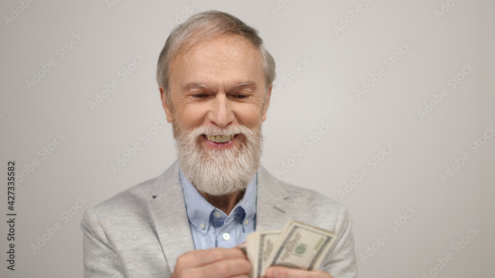 Successful old man having money in studio. Smiling guy counting dollars indoors. Successful old man having money in studio. Smiling guy counting dollars indoors.