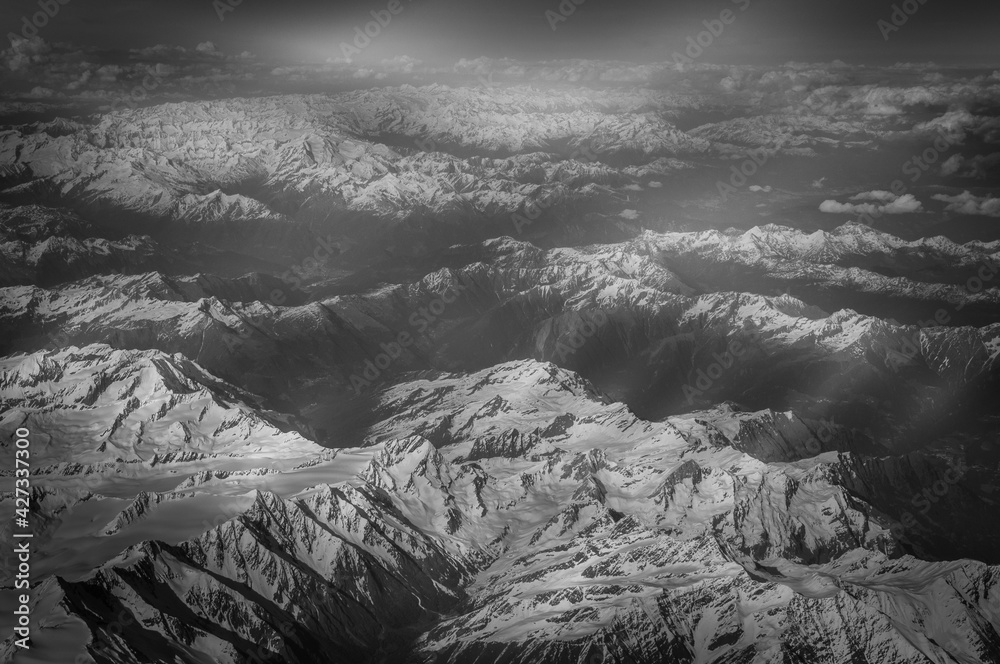 Black and white effect of snow-capped peaks and valleys of the Alps seen from the plane. Concept: geography, air travel, alps seen from above