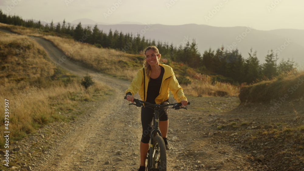 Fototapeta premium Woman on bicycle riding on path. Female bicyclist exercising in landscape