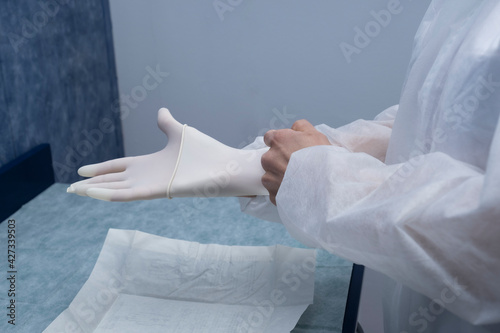 A doctor prepares to attend to a patient..The woman prepares (protective suits,googles,gloves and masks) all the necessary protections to protect itself from covid-19 photo